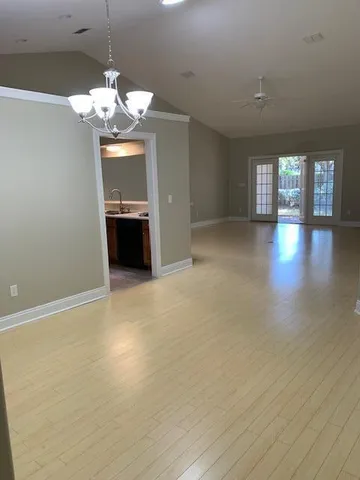 an empty room with chandelier and wooden floor