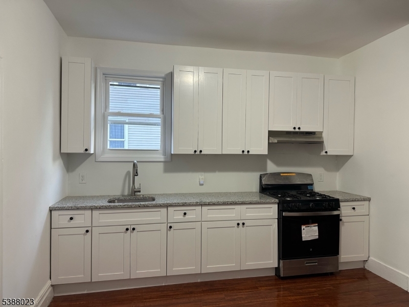 247 South 8th Street, Unit 1 Newark, NJ 07103 - Photo 1 of 13 a kitchen with granite countertop white cabinets and black appliances