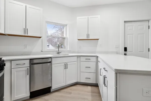 a kitchen with white cabinets appliances a sink and a window