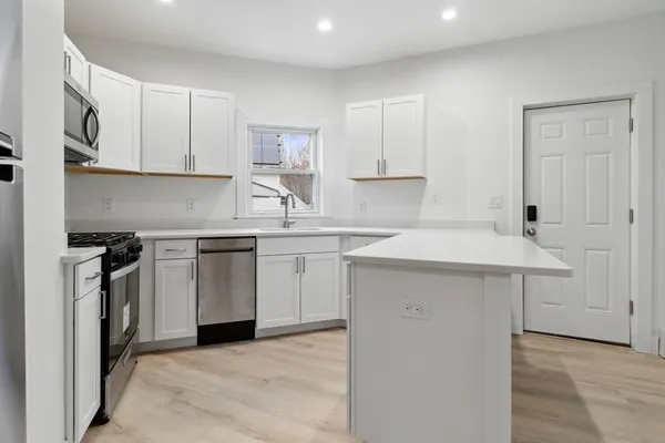 a kitchen with white cabinets sink and stove