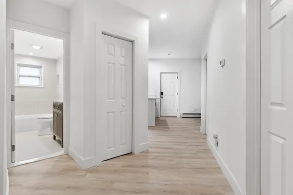 a view of a hallway with wooden floor and a bathroom