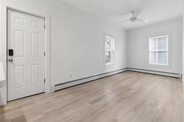 an empty room with wooden floor and windows