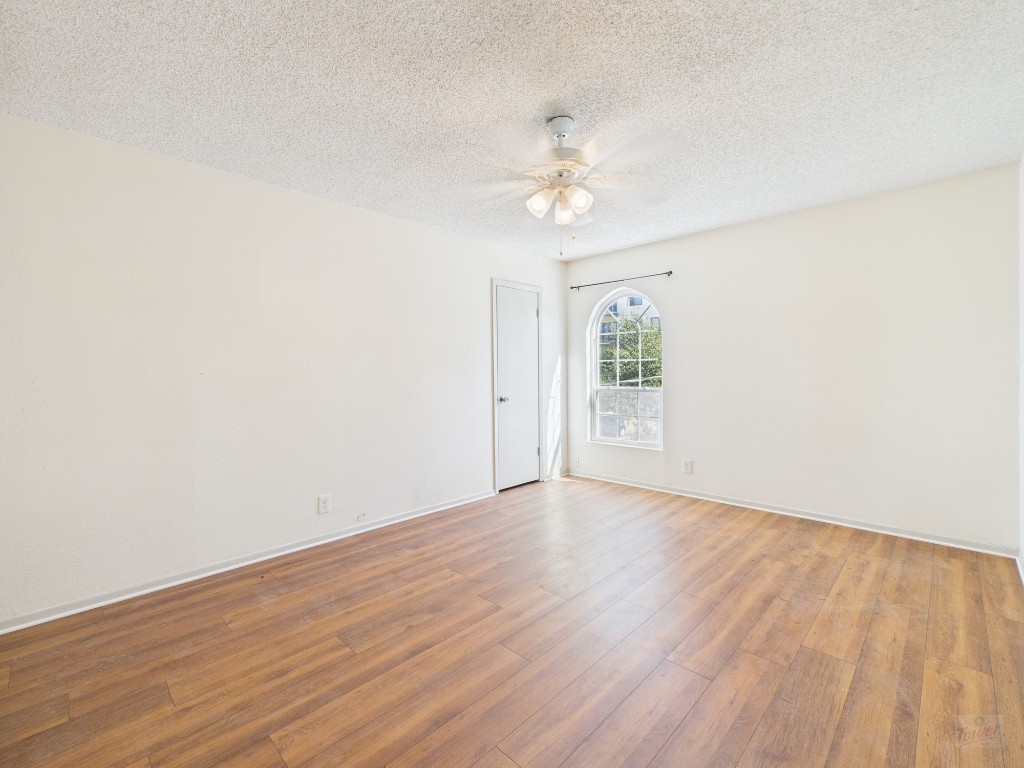 910 Duncan Lane, Unit 26 Austin, TX 78705 - Photo 27 of 31 an empty room with wooden floor chandelier fan and windows