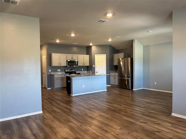 a kitchen with stainless steel appliances kitchen island granite countertop a refrigerator and a stove top oven