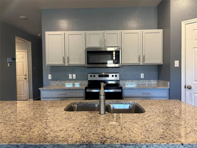 a kitchen with stainless steel appliances granite countertop a sink a stove a microwave a sink and cabinets