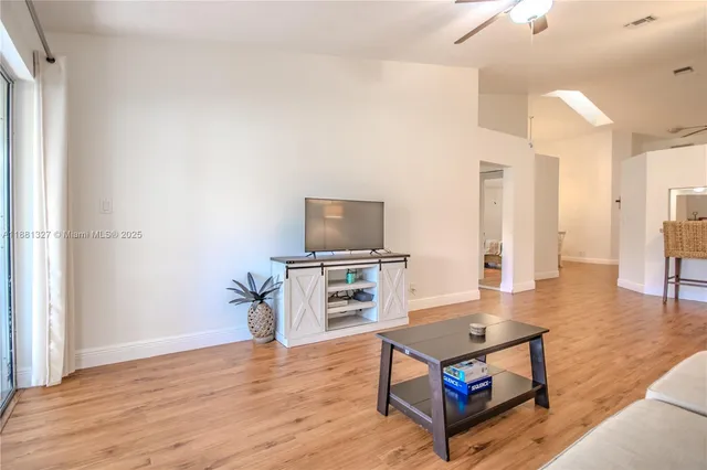 a living room with furniture a flat screen tv and kitchen view