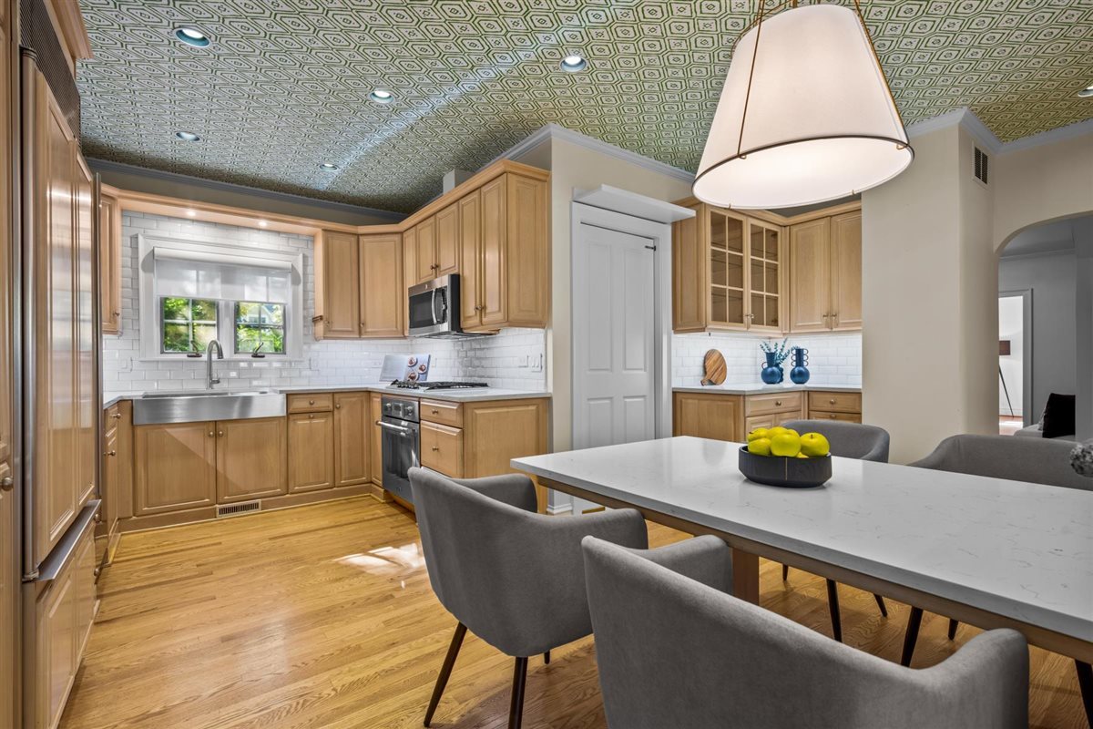 299 Vernon Avenue Glencoe, IL 60022 - Photo 7 of 42 a kitchen with a stove a sink a kitchen island with chairs and wooden cabinets