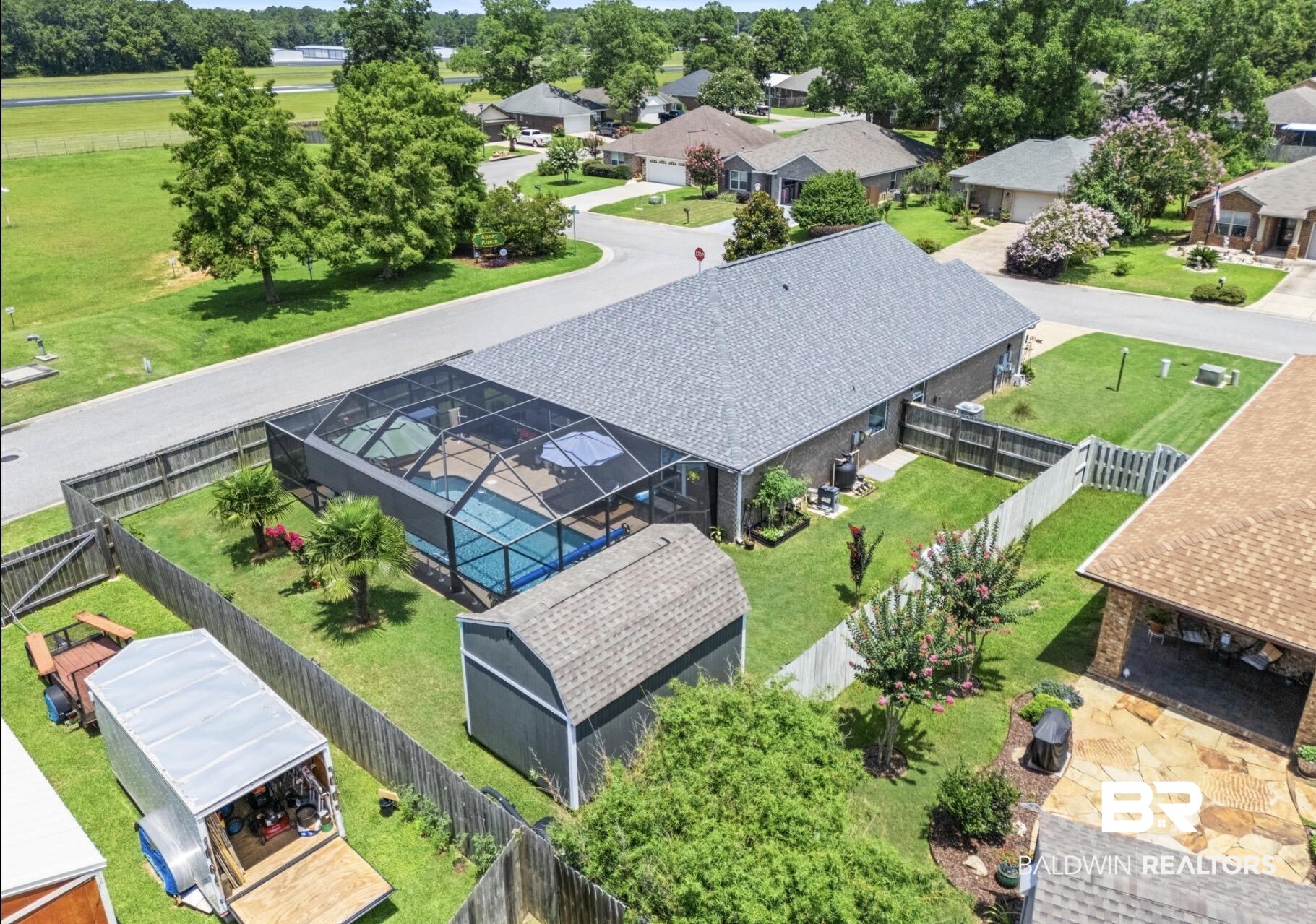 1676 Abbey Loop Foley, AL 36535 - Photo 2 of 31 Rear exterior featuring a screened-in swimming pool, a detached storage shed, a fenced yard, and mature landscaping