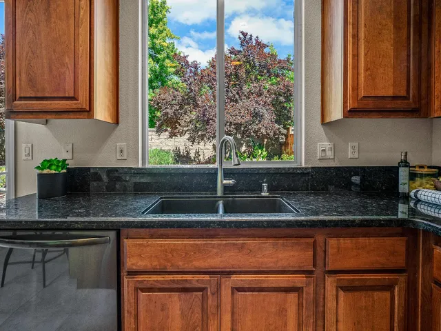 a kitchen with granite countertop a sink and white cabinets