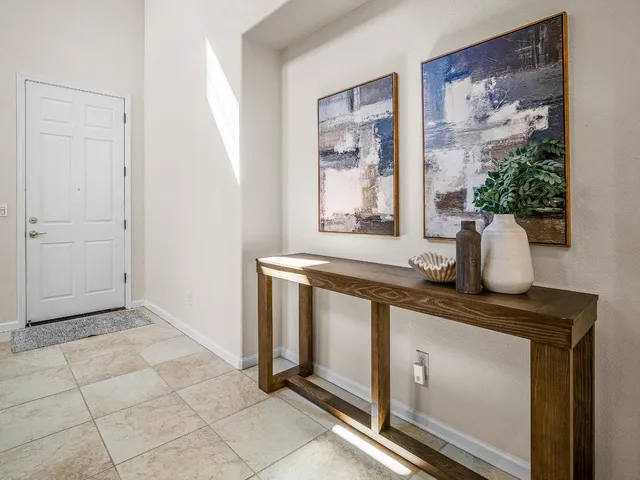 a hallway with painting on the wall and a potted plant