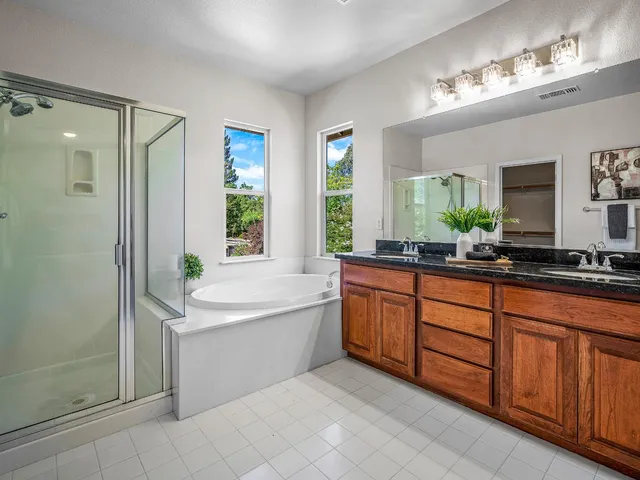 a large bathroom with a double vanity sink a large mirror and a bathtub