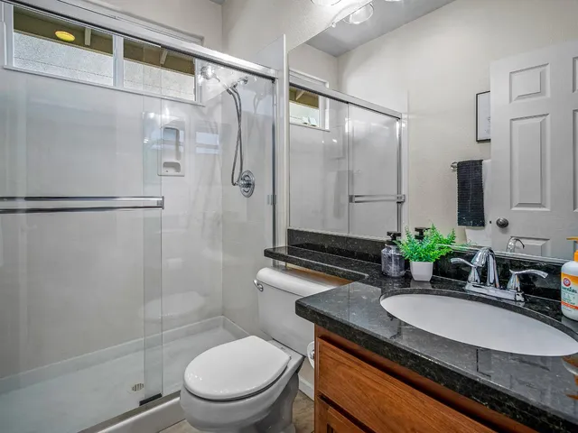 a bathroom with a granite countertop sink toilet a mirror and shower