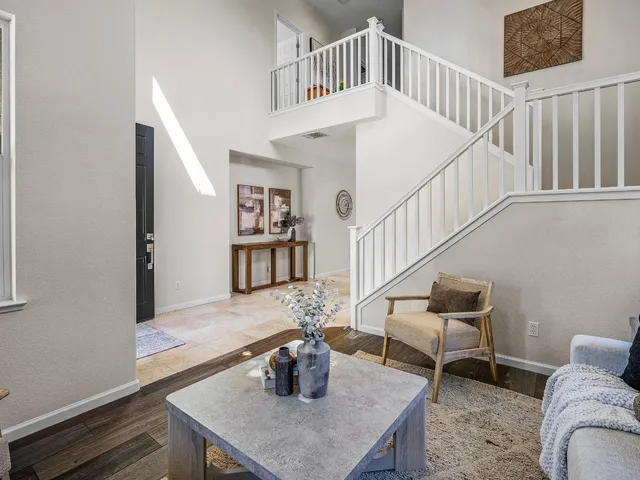 a living room with couches and a dining table with wooden floor