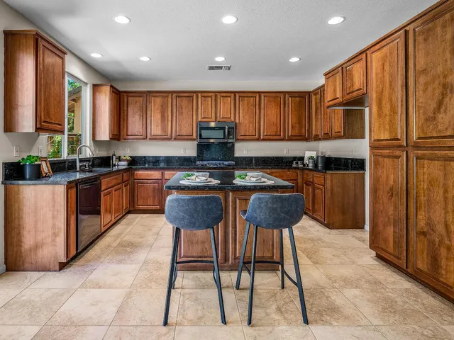 a kitchen with stainless steel appliances granite countertop a stove a sink a microwave a refrigerator and cabinets