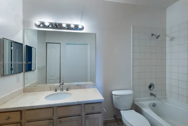 a bathroom with a granite countertop sink a toilet and shower