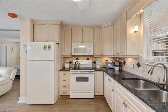 a kitchen with granite countertop white cabinets and white appliances