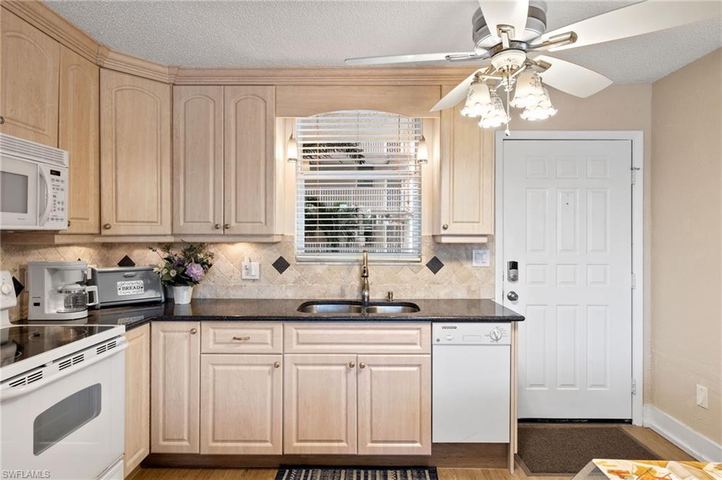5500 Bonita Beach Road Southwest, Unit 208 Bonita Springs, FL 34134 - Photo 2 of 14 a kitchen with granite countertop white cabinets and white appliances