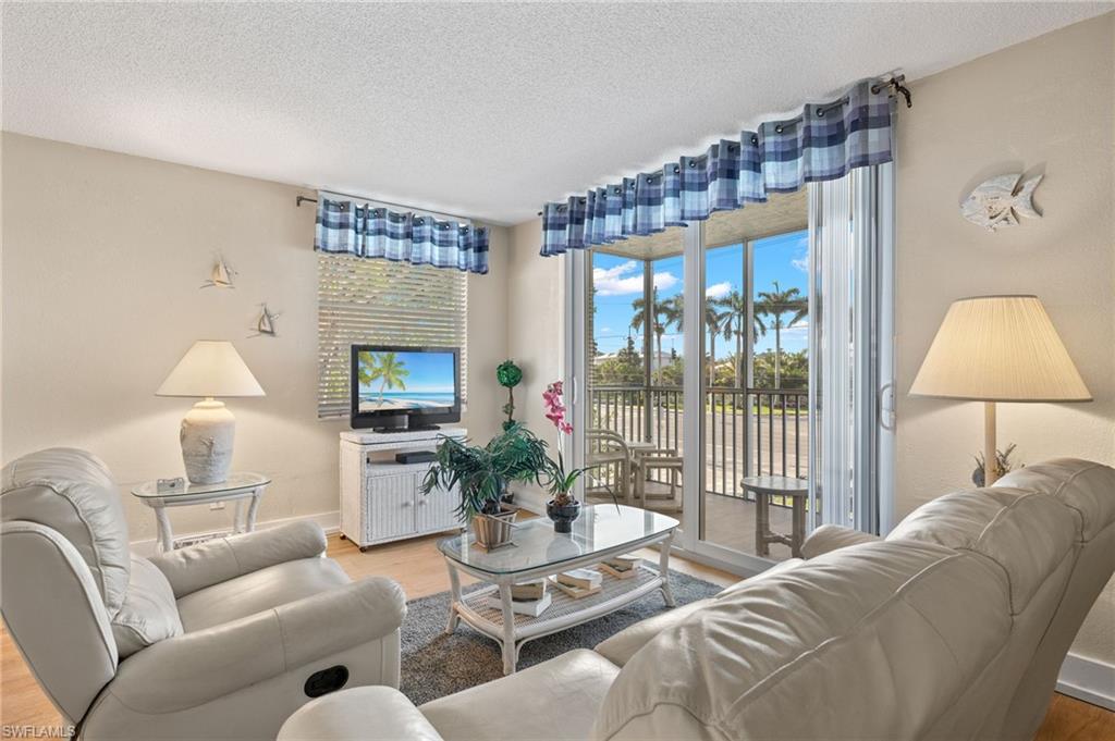 5500 Bonita Beach Road Southwest, Unit 208 Bonita Springs, FL 34134 - Photo 6 of 14 a living room with furniture a lamp and a floor to ceiling window