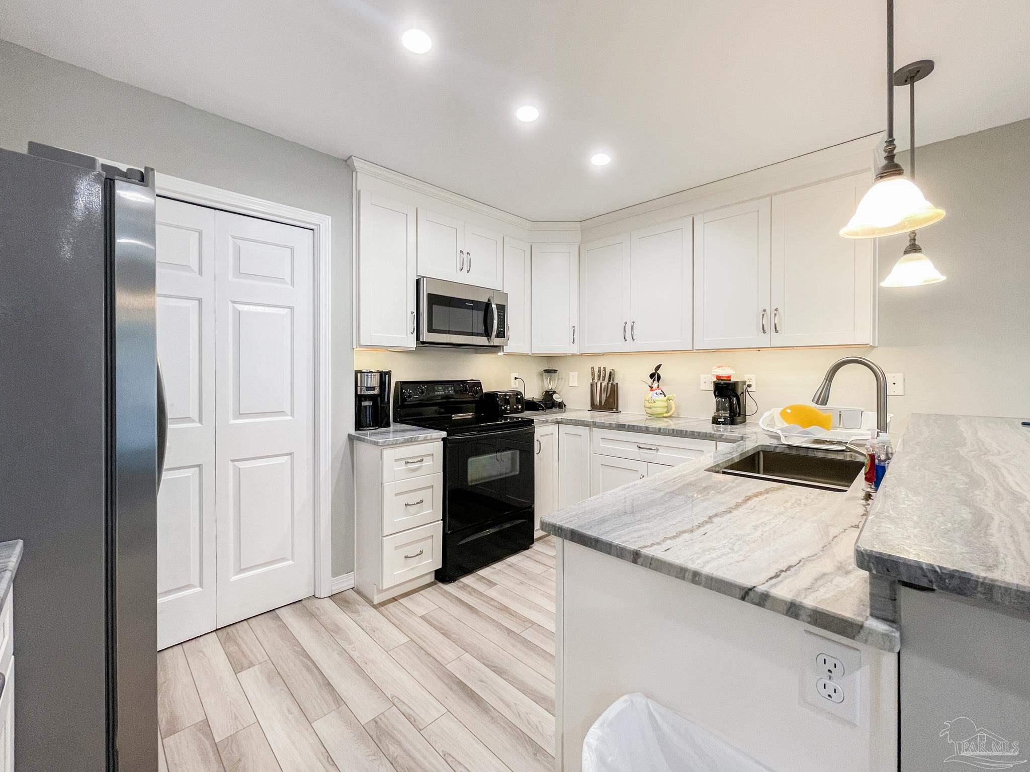 13351 Johnson Beach Road, Unit 402E Pensacola, FL 32507 - Photo 15 of 30 a kitchen with granite countertop a refrigerator stove top oven and sink