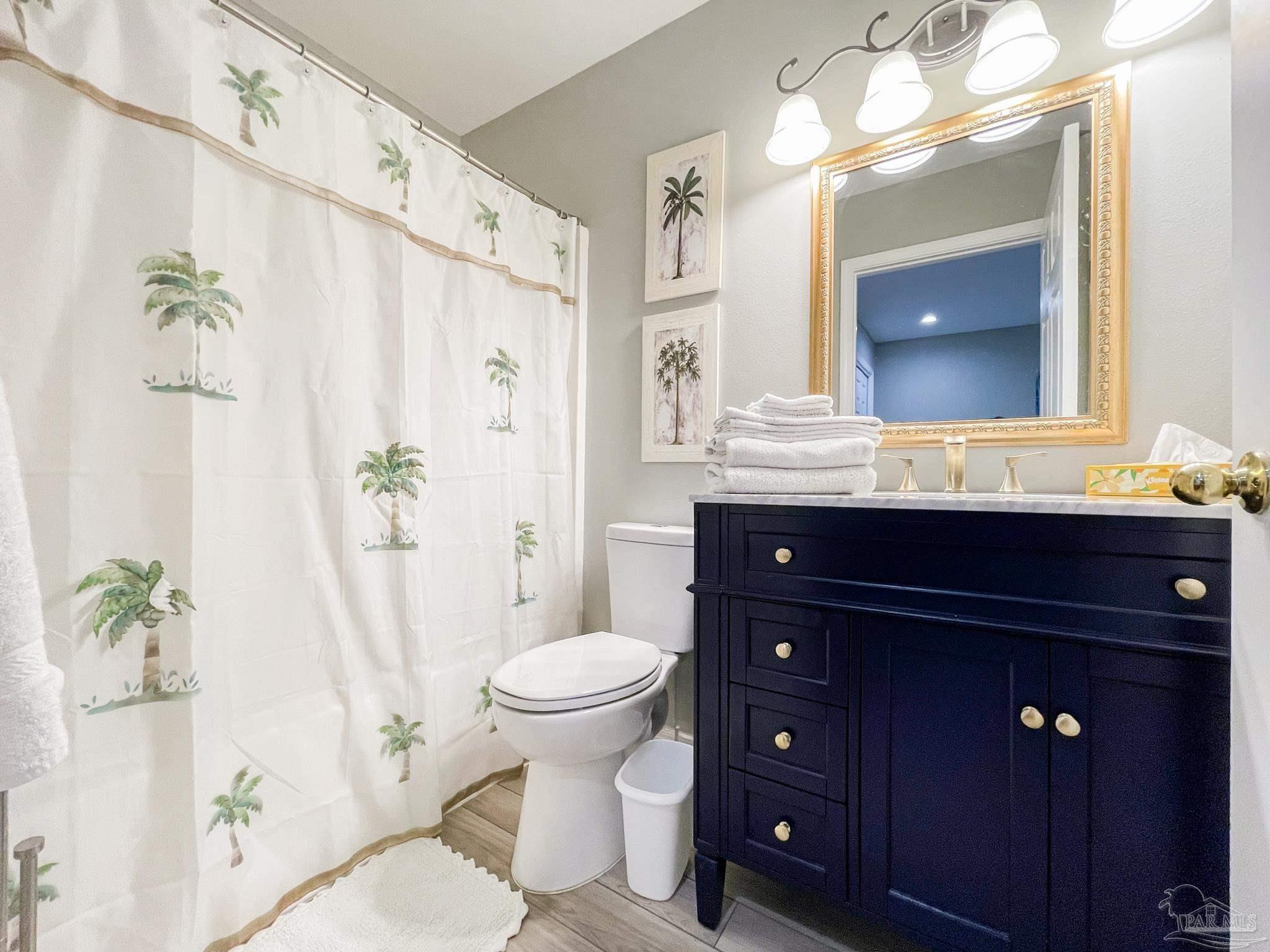 13351 Johnson Beach Road, Unit 402E Pensacola, FL 32507 - Photo 27 of 30 a bathroom with a granite countertop sink toilet a mirror a vanity and shower