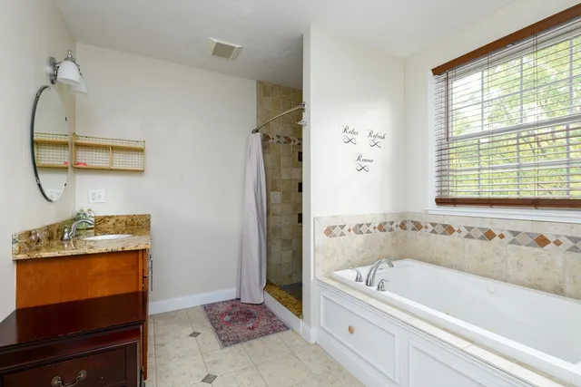 a bathroom with a tub sink and mirror