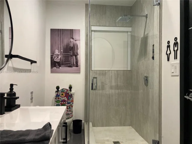 a bedroom with a bed and a lamp on dresser next to a window