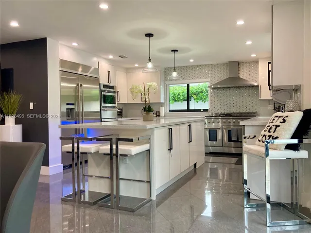 a kitchen with stainless steel appliances granite countertop a stove top oven a sink dishwasher a dining table and chairs with wooden floor