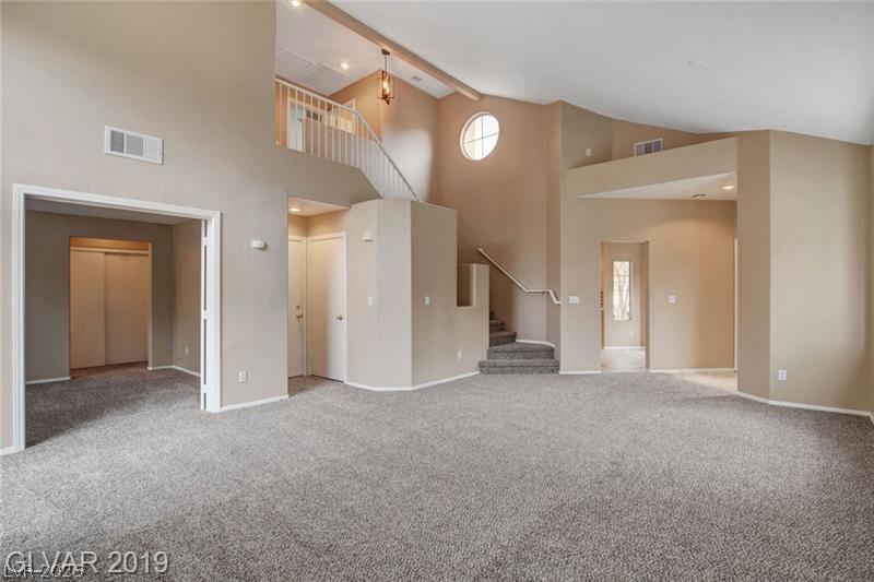 2647 Ridgewater Circle Henderson, NV 89074 - Photo 8 of 26 Vaulted ceilings soar over a sprawling open-concept living area with classic carpet flooring.