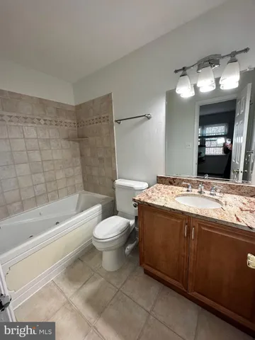 a bathroom with a granite countertop sink a toilet mirror and bathtub