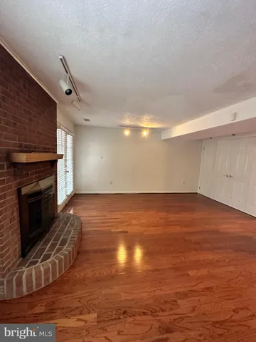a view of empty room with wooden floor and fireplace