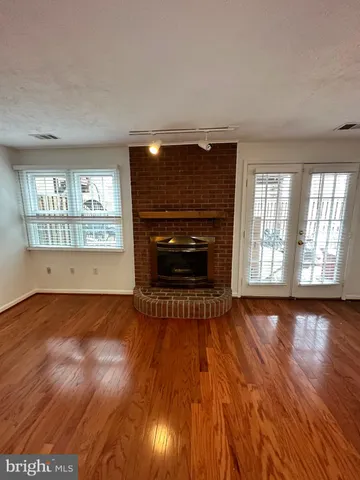 an empty room with wooden floor fireplace and windows