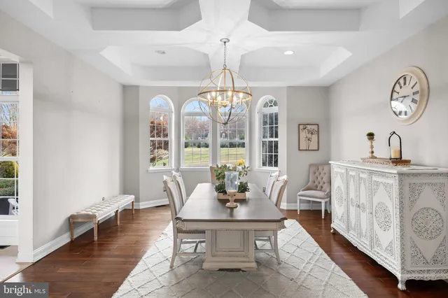 a dining room with wooden floor a chandelier a wooden table and chairs