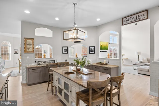 a kitchen with stainless steel appliances kitchen island granite countertop a table chairs in it and wooden floors