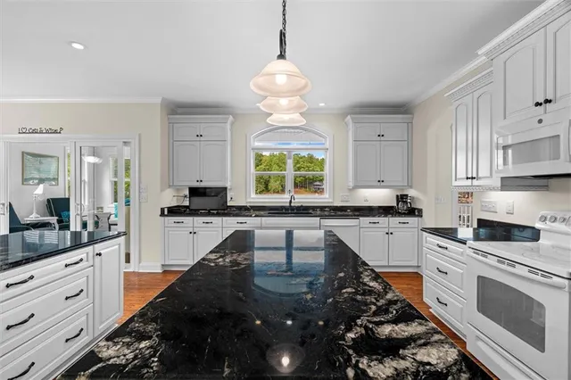 a kitchen with granite countertop white cabinets and white appliances