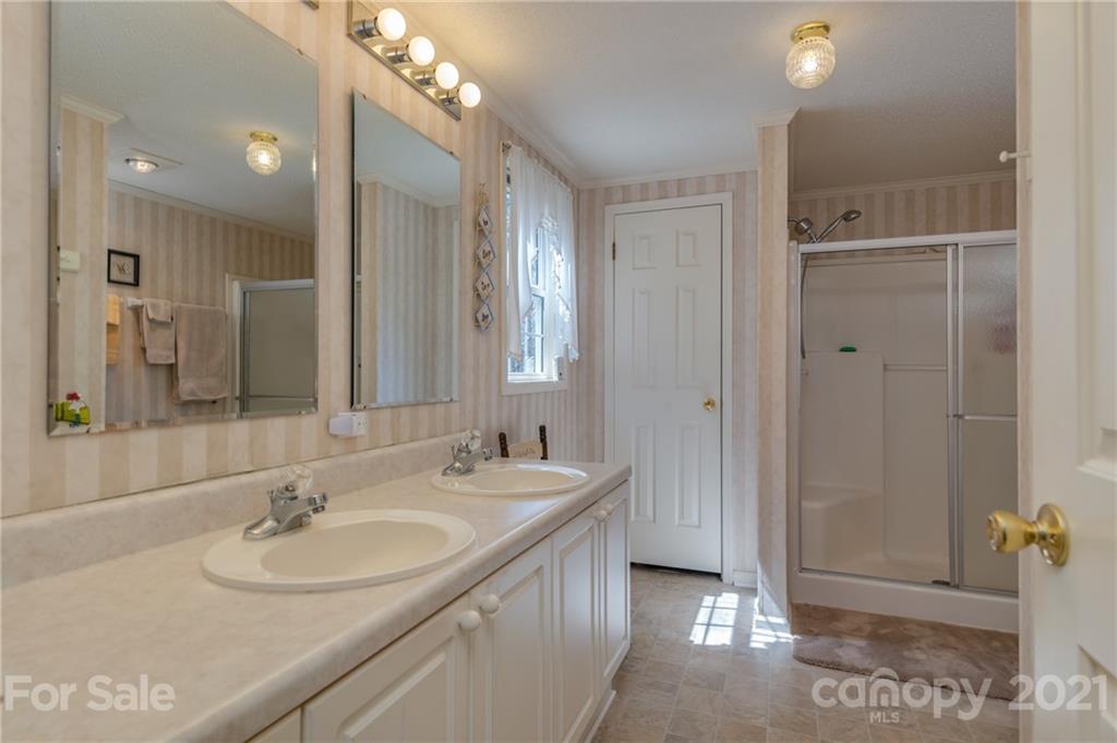 569 Flynn Road Rutherfordton, NC 28139 - Photo 19 of 34 a bathroom with a double vanity sink a mirror and a shower