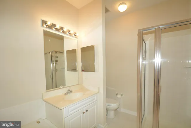 a bathroom with a granite countertop sink a toilet and shower