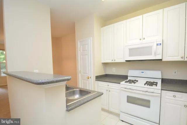 a kitchen with granite countertop white cabinets and white appliances