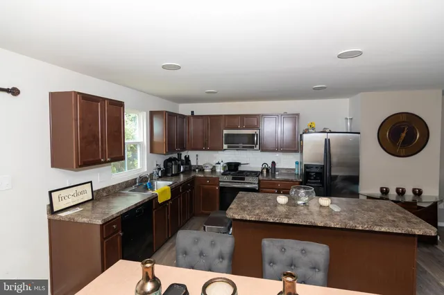 a kitchen with kitchen island granite countertop a sink dishwasher stove and oven with cabinets