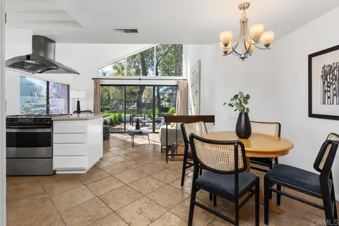 a kitchen with stainless steel appliances kitchen island granite countertop a table chairs in it and wooden floors