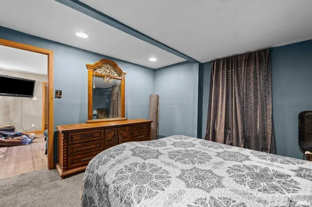 a bedroom with a bed and a large mirror on the dresser