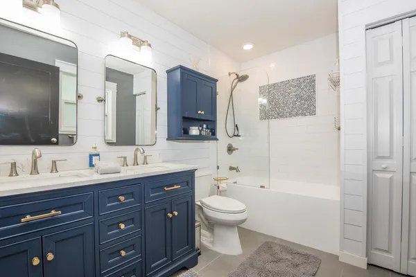 a bathroom with a toilet a double vanity sink and a mirror