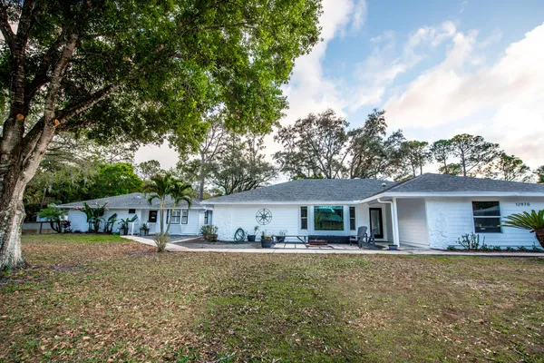 a front view of house with yard and trees in the background