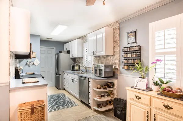 a kitchen with stainless steel appliances a sink a stove a refrigerator cabinets and a window