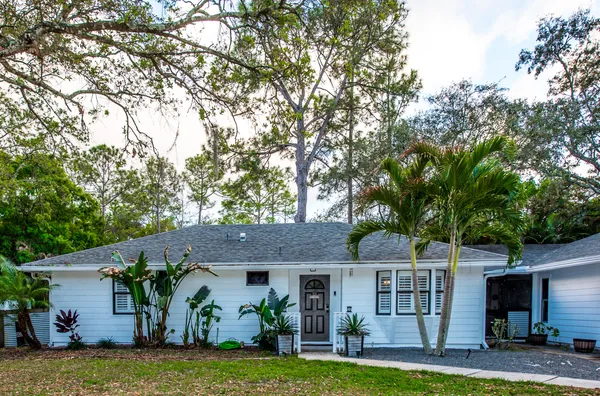 a front view of a house with a garden and trees