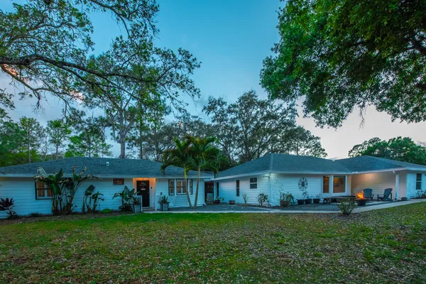 a front view of a house with a garden and trees