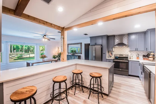 a kitchen with stainless steel appliances granite countertop a stove a refrigerator a sink a dining table and chairs with wooden floor