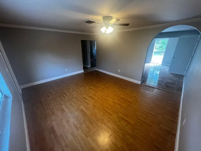 an empty room with wooden floor and windows
