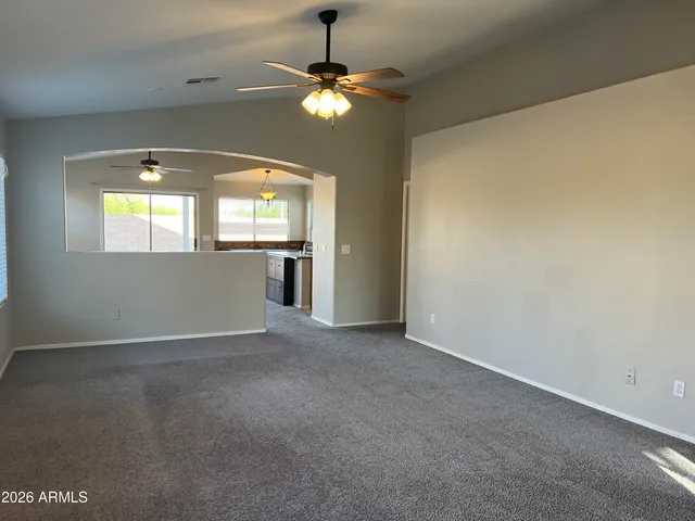 an empty room with a chandelier fan and windows