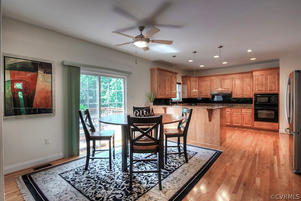 13340 Eppes Falls Road Chesterfield, VA 23838 - Photo 15 of 50 a kitchen with stainless steel appliances granite countertop a stove top oven a sink a dining table and chairs with wooden floor