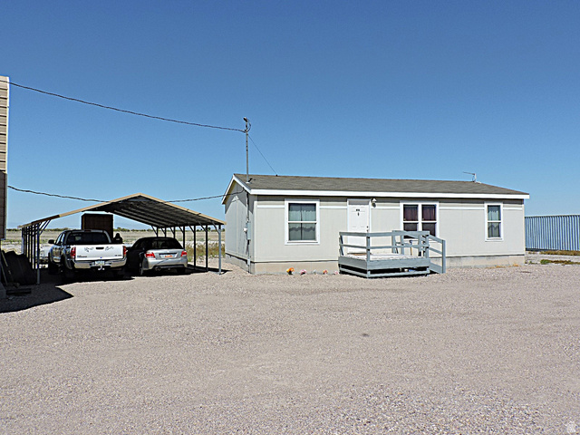 915 North 5000 W Road Hinckley, UT 84635 - Photo 20 of 27 Single-story residence featuring a gravel lot, a covered carport, and a front entry deck